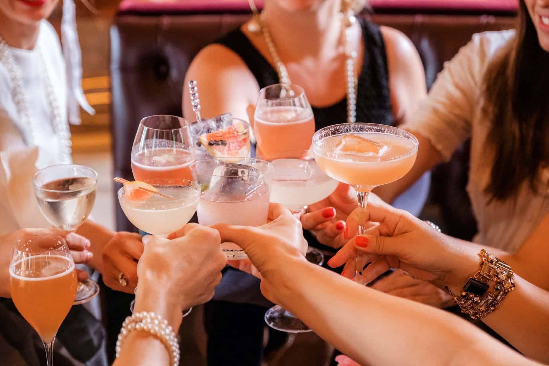 Cocktail glasses with colorful drinks, women celebrating together at a social gathering in Stockholm.