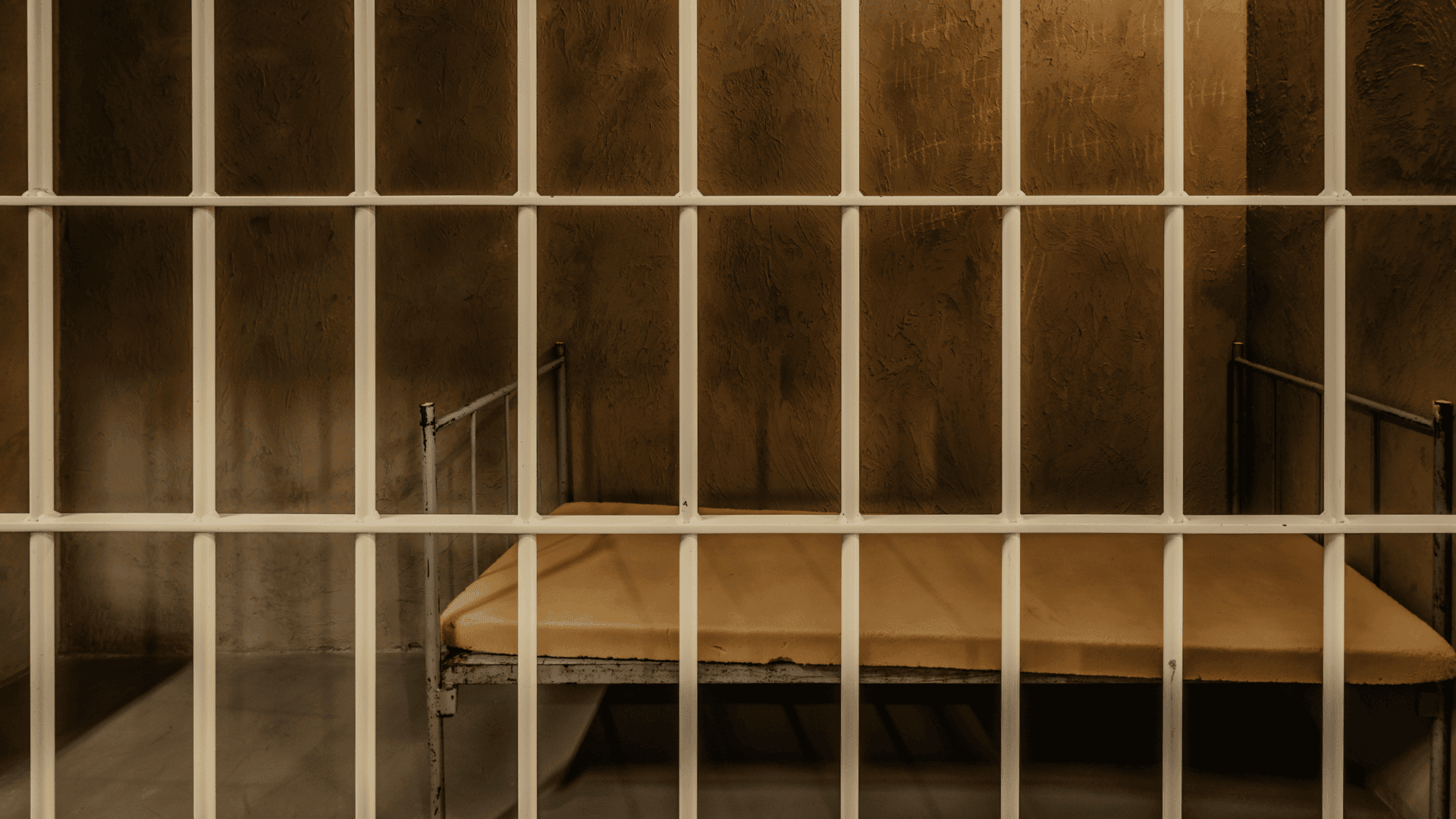 Prison cell with metal bars and a bed inside at Roomescape by Fox in a Box Stockholm.